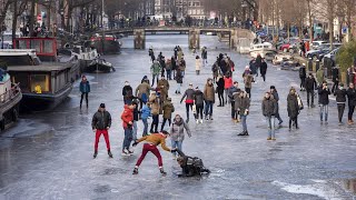 Ice skaters glide over frozen canal in Amsterdam [upl. by Kcirdneh918]