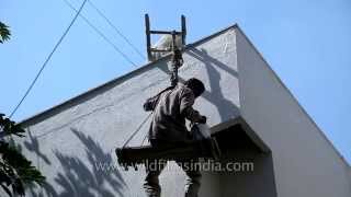 Indian workers paint a building sitting on a makeshift wooden swinglike plank [upl. by Airrehs]