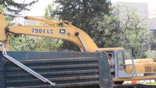 Deere 790ELC excavator loading a blue dump truck and digging a trench on a road construction site [upl. by Noxid23]